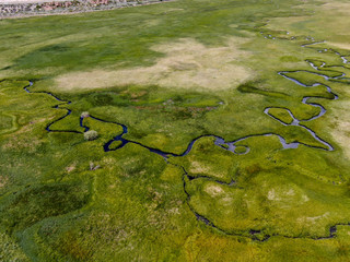 Aerial top view of green land and small curve river in Aspen Springs, Mono County California, USA