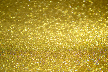 Abstract blurred background of golden glitter light partly in focus.