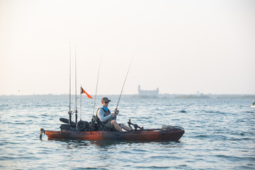 Obraz premium Young Man Kayak Fishing at Sunrise in Canada