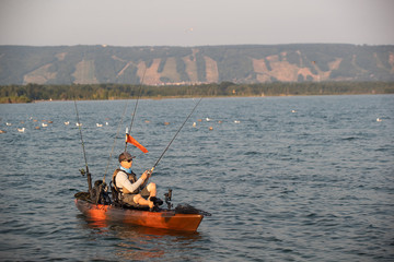 Obraz premium Young Man Kayak Fishing at Sunrise in Canada