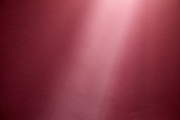 A pink ray of light illuminates a finely textured dark pink backgroundA pink ray of light illuminates a finely textured dark pink background