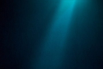 Blue ray of light falls on a dark blue textural background