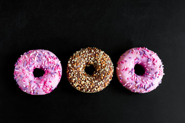 top view flat lay berry and chocolate doughnuts on a black background