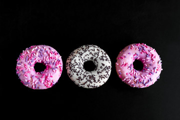 top view white and pink doughnuts on a black background