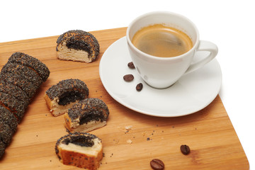 Cookie with poppy seeds on cutting board and white cup of black coffee