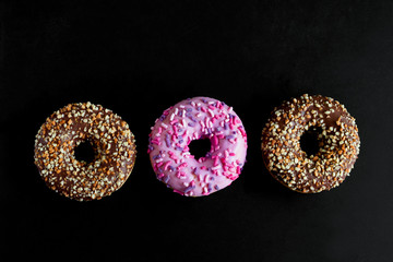 top view flat lay berry and chocolate doughnuts on a black background