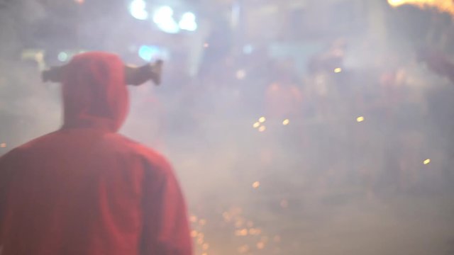 fire procession on a city street at night, slow motion, blured. people in costumes of devils with torches