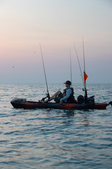 Obraz premium Young Man Kayak Fishing at Sunrise in Canada