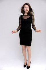 Horizontal Portrait of a pretty slim beautiful fashionable adult girl with beautiful brunette hair in a black dress. It should be in full growth, talking showing different poses and emotions