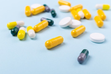 Multicolor tablets and pills capsules on blue background Heap of assorted various medicine tablets and pills. Health care Close-up Copy space