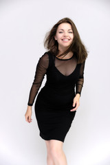 Horizontal Portrait of a pretty slim beautiful fashionable adult girl with beautiful brunette hair in a black dress. It should be in full growth, talking showing different poses and emotions
