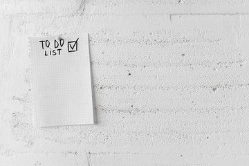 To-do list to fill out on a paper sheet is hanging on the left on a white wall