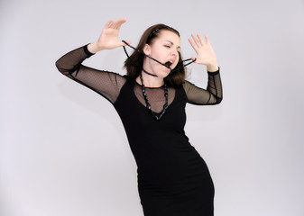Portrait on white background of a pretty slim beautiful fashionable adult girl with beautiful brunette hair in a black dress. Standing talking demonstrating different poses and emotions