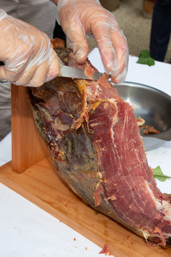country red ham cut by the chef professional cutter carving slices from whole bone in serrano ham
