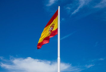 Spanish flag flutters against  blue sky in the wind