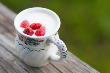 Natural yogurt with strawberry in a porcelain mug on a wooden table. Summer healthy dessert. 