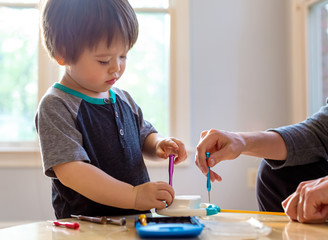 Toddler boy playing with tools and helping fix his toy