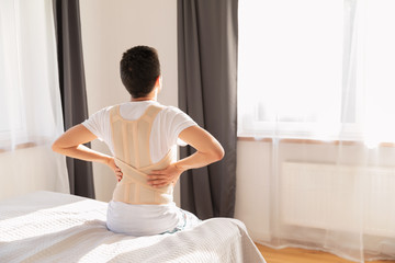 Young man wearing a back support belt. Lumbar brace, back support for back trauma or muscle back...