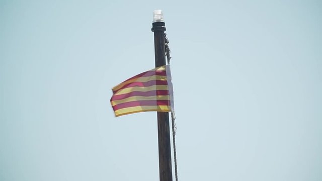 the flag of Catalonia on the mast of the boat develops in the wind