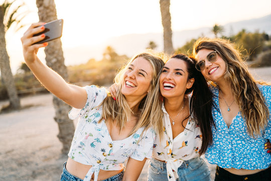 Group of three women friends making a selfie in a beach during a summer day. Friendship and holiday.