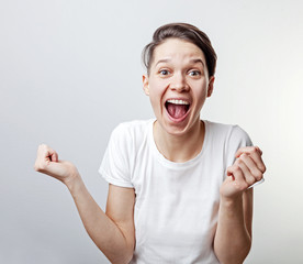 Yes. Pretty extremely happy woman celebrating her success with raised hands. Girl isolated on white background.