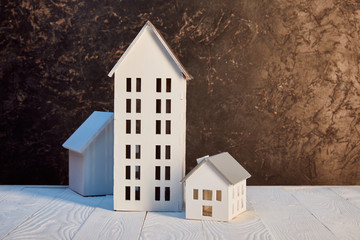 houses models on white wooden table near brown textured wall, real estate concept