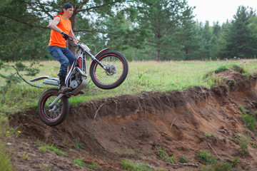 Motorcycle rider Caucasian man jumping in sandy pit with his trial bike, copy space