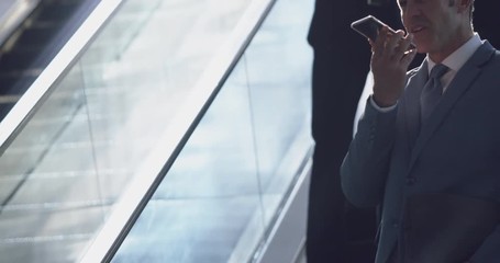 Businessman using mobile phone on escalator in a modern office 4k - Powered by Adobe