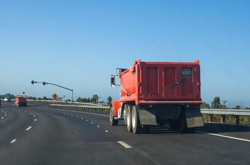 Rear view of red heavy duty industrial truck on California highway.