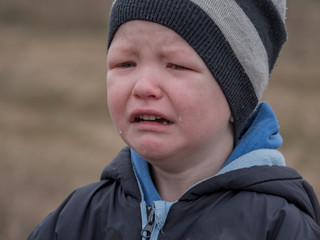Blonde boy cries with tears. Upset child. Violence in family over children. Concept of bullying,...