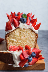 Buttercream berry pound cake with slice, colorful fruits and berries on top