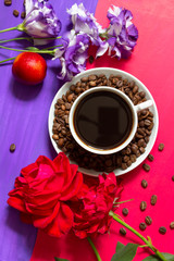A cup of black coffee on a blue and red bright two-color background with coffee beans and flowers of rose and eustoma. Bright, contrasting, summer, coffee design with a place for text.