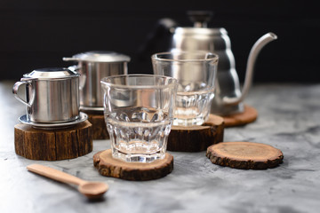 Glasses, phin coffee makers and goose neck kettle on wood slabs ready for making Vietnamese drip...