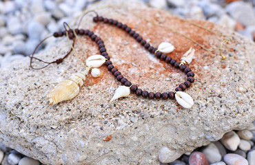 still life of necklaces with shells on the beach - summer jewelry advertisement