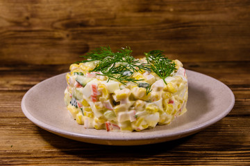 Salad with crab sticks, boiled eggs and cucumbers on a ceramic plate