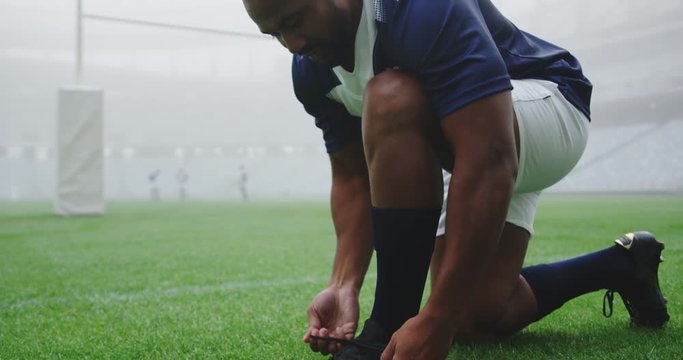 Rugby player tying shoelaces in the stadium 4k