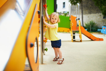Adorable toddler girl near playground slide