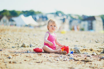 Adorable toddler girl playing with sand on the beach