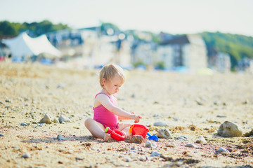 Adorable toddler girl playing with sand on the beach