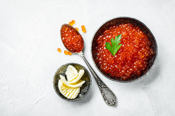 Delicious red caviar in black bowl on a light concrete background. Top view with copy space. Flat lay