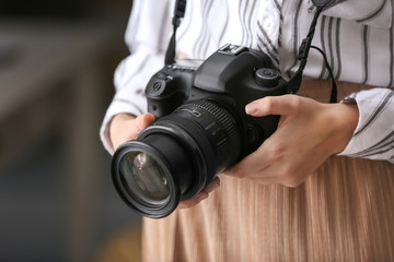 Young girl with modern photo camera at home, closeup