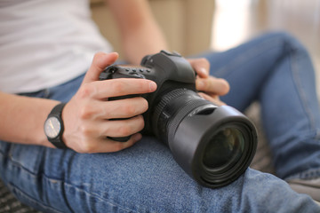 Teenage boy with photo camera at home, closeup
