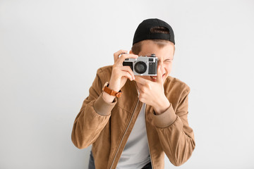 Teenage boy with photo camera on light background