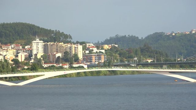 View of Mondego river with water fountain and Pedro e Ines pedestrian bridge, Coimbra, Portugal