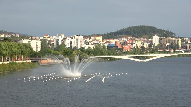 View of Mondego river with water fountain and Pedro e Ines pedestrian bridge, Coimbra, Portugal
