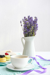 Beautiful lavender flowers with cup of coffee on white table