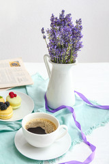 Beautiful lavender flowers with cup of coffee on white table