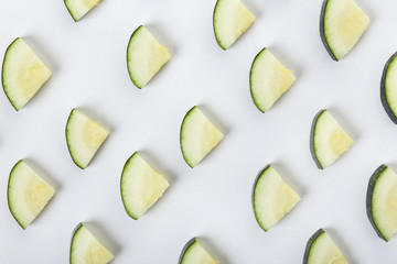 Slices of fresh zucchini squash on white background