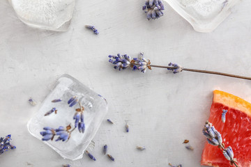 Lavender flowers with ice cubes and grapefruit slice on grey background