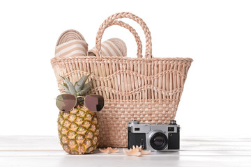 Beach bag and accessories on table against white background